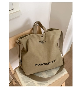 Detail of khaki canvas tote bag with black typography on a wooden chair and book