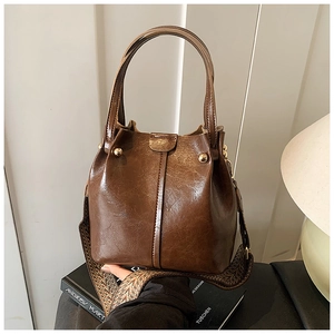 Close-up of vintage brown leather bucket bag with geometric patterned wide strap