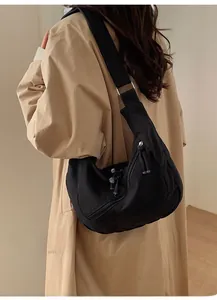 Close-up of black canvas crossbody bag with large capacity and adjustable strap on model