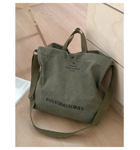 Detail of army green canvas tote bag with adjustable strap on light wood floor