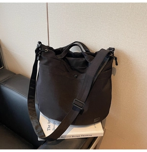 Close-up of black crossbody bucket bag with drawstring closure on white books
