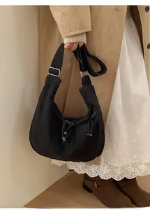 Close-up of black crescent dumpling bag with adjustable silver buckle and woven zipper pull