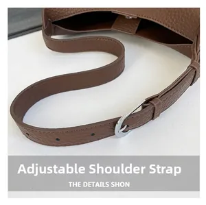 Close-up of adjustable brown litchi pattern shoulder strap with silver metal buckle