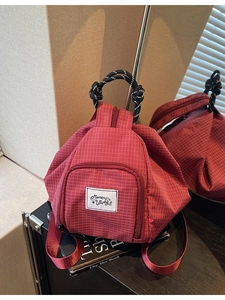 Red checkered canvas backpack with woven handles and large capacity for travel