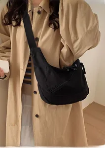Macro shot of large black crescent crossbody bag showing fabric texture and strap detail