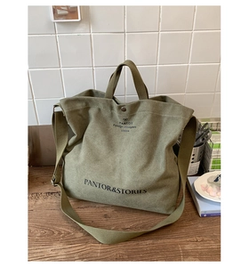 Close-up of olive green canvas tote bag with adjustable strap and vintage print detail