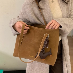 Close-up of brown matte tote bag featuring a cute dachshund pendant and gold brand logo