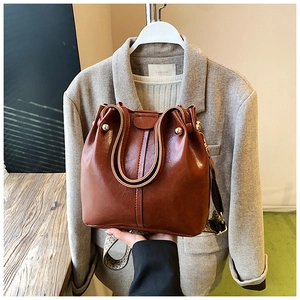 Brown leather bucket bag detail with vintage patterned wide strap and gold hardware rivets