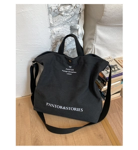 Close-up of black canvas tote bag with white typography and durable metal buckle