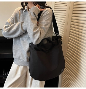 Macro detail of black nylon crossbody bag with drawstring closure and wide strap