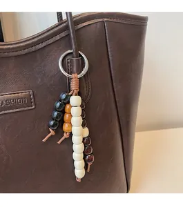 Close-up of ethnic style beaded pendant on brown leather tote with fashion embossing