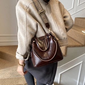 Detail of vintage dark brown bucket bag featuring wide geometric textile strap and glossy leather