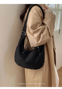 Sac bandoulière demi-lune noir minimaliste porté par un mannequin avec bandoulière réglable