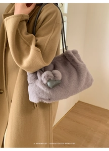 Detail der lila Kunstpelz-Beuteltasche mit grauem Herzanhänger und Schultergurt
