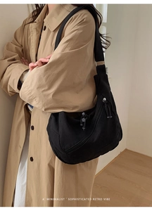 Side view of model wearing a black large canvas crossbody bag with retro double zippers