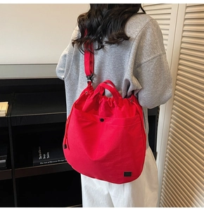 Detail of red drawstring canvas tote bag with magnetic outer pocket and woven logo label