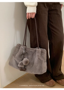 Detail einer flauschigen Plüsch-Tasche in Taupe mit Lederriemen und Herzanhänger-Dekor