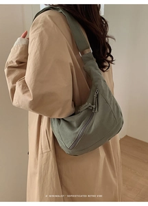 Side view of olive green crescent messenger bag on beige trench coat for casual look
