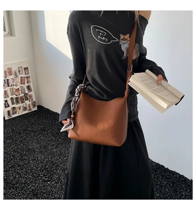 Dettaglio borsa a secchiello in pelle martellata marrone con foulard a pois alla moda