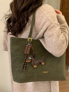 Olive green suede tote bag with dog charm shown on shoulder for a commute style