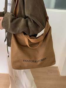 Brown canvas tote bag with black letter print and wide shoulder strap for women
