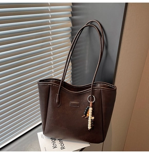 Détail du sac cabas marron vintage avec étiquette FASHION et breloque perlée chic