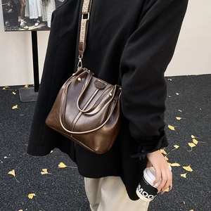 Detailed view of deep brown bucket bag with vintage pattern wide shoulder strap