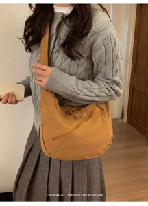Gros plan du sac bandoulière en toile jaune moutarde avec détail de fermeture à pompon