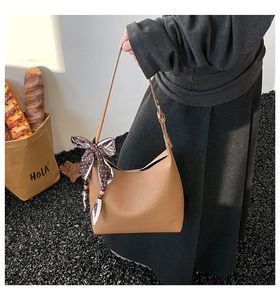 Dettaglio borsa a secchiello in pelle martellata marrone con foulard a pois in seta