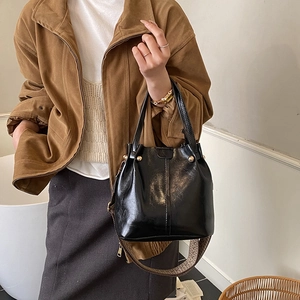 Fashionable black bucket bag with a jacquard wide strap and glossy leather finish