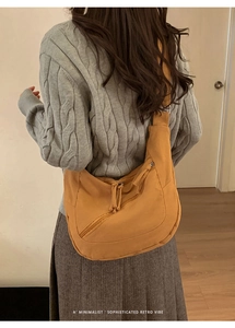 Close-up of mustard yellow canvas crossbody bag featuring a retro crescent design and tassel