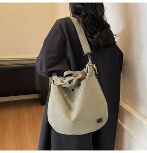 Detail of olive green canvas crossbody bag with adjustable strap and square logo