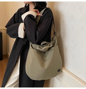 Detail of army green canvas crossbody bag showing high-capacity design and wide shoulder strap