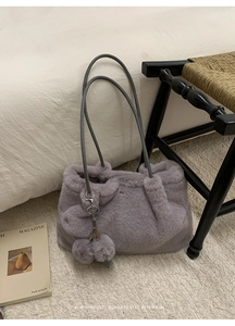 Detail der lila Kunstfell-Einkaufstasche mit grauen Ledergriffen und Pelzball-Anhänger