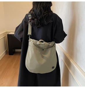 Detail showing the large capacity and draping effect of the olive canvas crossbody bag