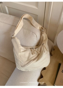 Gros plan du sac demi-lune en toile crème avec bandoulière et détails de fermeture