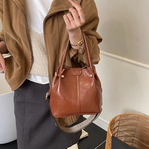 Brown vintage PU bucket bag featuring ethnic woven wide strap and magnetic closure