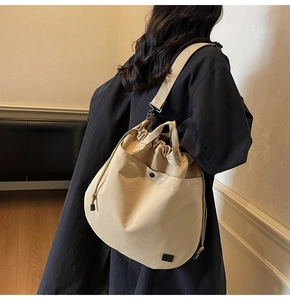 Detail view of a beige canvas drawstring crossbody bag with adjustable shoulder strap