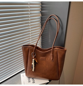 Vue détaillée du sac cabas marron en similicuir avec étiquette et pompon perlé