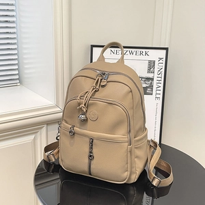 Detail eines khakifarbenen Lederrucksacks mit Metallreißverschlüssen auf schwarzem Tisch
