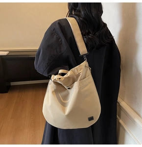 Close-up of adjustable wide shoulder strap on high-capacity beige canvas crossbody bag