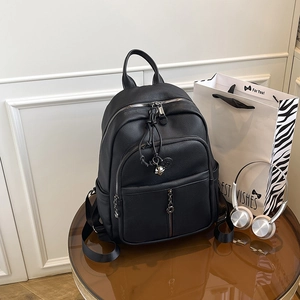 Detail eines schwarzen Lederrucksacks mit Metallkette und dekorativem Glockenanhänger