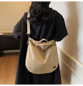 Rear view of a model wearing the beige canvas crossbody bag with adjustable black strap
