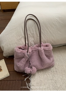 Makroaufnahme der lila Kunstpelz-Tasche mit braunem Ledergurt und doppelten Pelzpompons