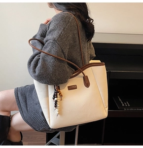 Détail du sac cabas beige texturé avec lanières brunes et breloque en perles de bois