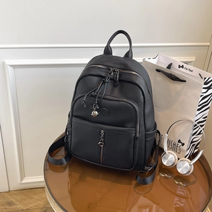 Detail eines schwarzen Lederrucksacks mit Multi-Taschen-Design auf einem braunen Glastisch