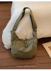 Detail of olive green canvas crescent bag showing double front zippers and wide strap
