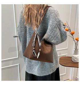 Close-up of brown litchi pattern leather tote bag with stylish printed silk scarf detail