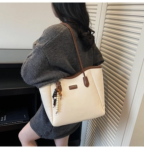 Détail du cabas en cuir blanc avec étiquette Fashion et pampille en perles