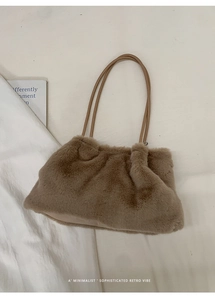 Detail einer braunen Plüsch-Tasche mit Lederriemen auf weißem Stoffhintergrund